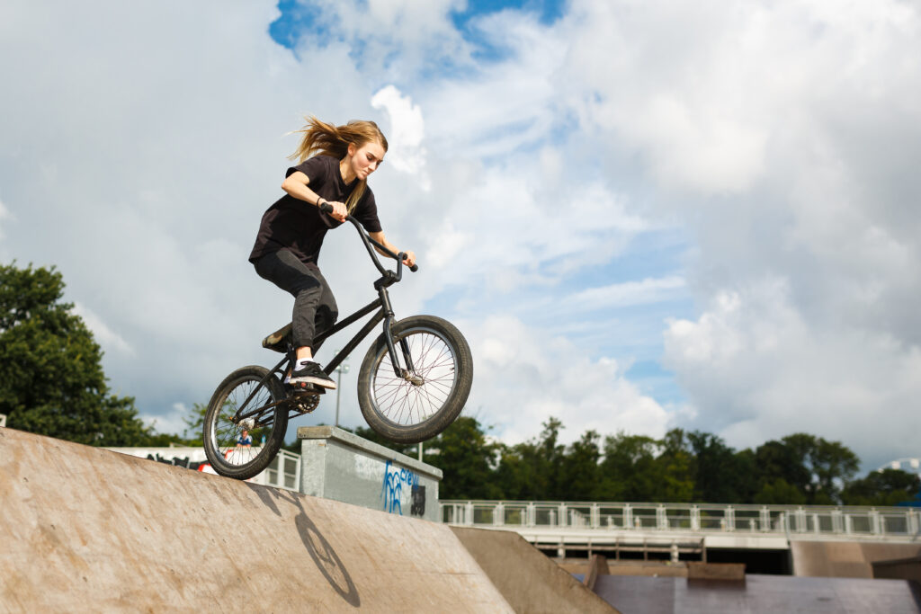 BMX rider is jumping over ramp outdoors